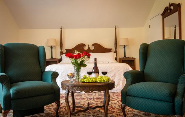 The Cottage interior with a bed in the background, and two armchairs and a table in the foreground